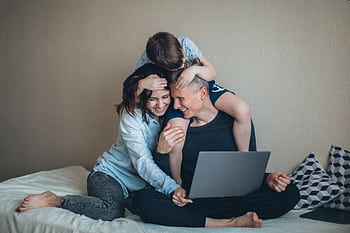 Family enjoying time together while working on a laptop at home. HD wallpaper