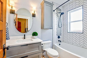 Elegant modern bathroom featuring chevron tiles, oval mirror, and sleek fixtures for a contemporary look. HD wallpaper