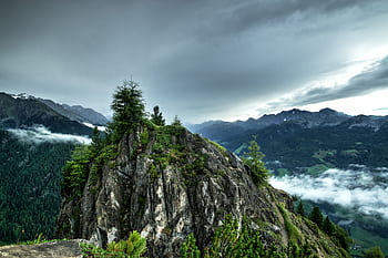 Stunning high-angle view of a dramatic mountain landscape with lush greenery and clouds. HD wallpaper