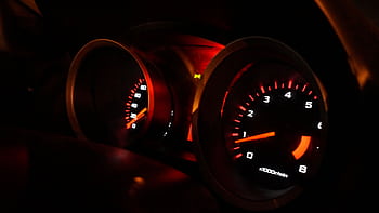 A detailed view of illuminated car gauges on the dashboard at night. HD wallpaper