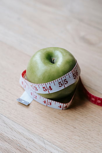 A green apple encircled by a measuring tape, symbolizing diet and fitness goals. HD phone wallpaper