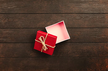Top view of an open red gift box tied with twine on a wooden surface. HD wallpaper