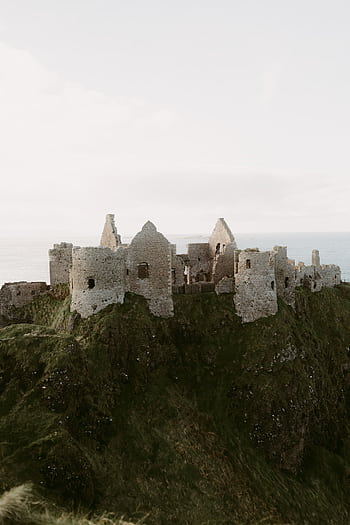 Explore the iconic ruins of Dunluce Castle perched on the dramatic cliffs of Northern Ireland. HD phone wallpaper