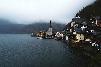 A serene, foggy morning in Hallstatt, Austria, showcasing calm waters and historic architecture. HD wallpaper