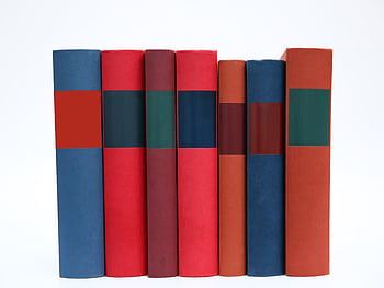 A row of colorful books with plain spines arranged on a white surface. HD wallpaper