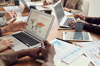 Group of professionals collaborating on project with laptops and documents in a modern office. HD wallpaper