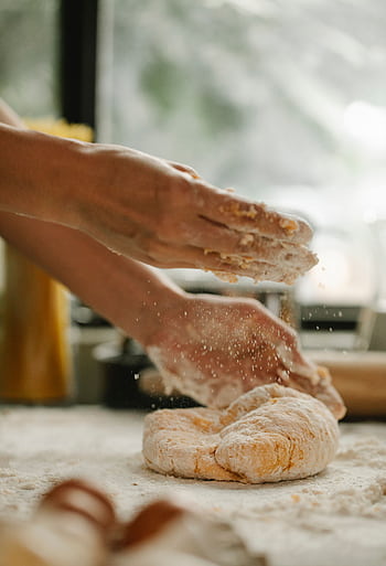 A baker kneading dough on a floured surface in an artisan bakery kitchen. HD phone wallpaper