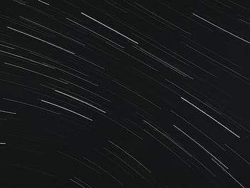 Captivating long exposure of star trails streaking across the night sky, evoking a sense of motion and wonder. HD wallpaper