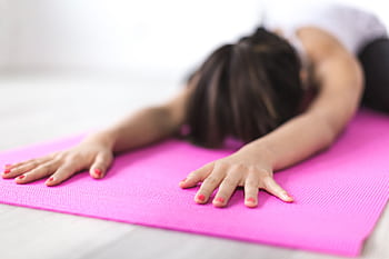 Close-up of woman stretching on a pink yoga mat, promoting relaxation and mindfulness. HD wallpaper