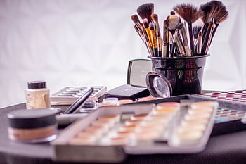 Close-up of a professional makeup brush set and cosmetics on a table for beauty use. HD wallpaper