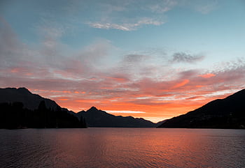 A breathtaking of a lake reflecting a vibrant sunset with silhouetted mountains. HD wallpaper