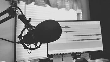 Black and white of a podcast setup with micro and waveform screen. HD wallpaper