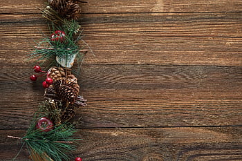 Rustic Christmas-themed decoration with pine cones and berries on a wood surface. HD wallpaper