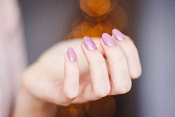 A close-up of a woman's hand displaying a stylish pink glitter manicure, highlighting nail art details. HD wallpaper