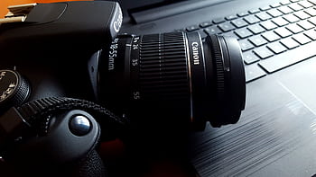 Close-up of a black DSLR camera with lens on a laptop keyboard. HD wallpaper