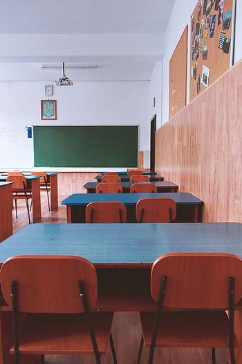 A tranquil empty classroom with wooden furniture and a green chalkboard, perfect for educational themes. HD phone wallpaper