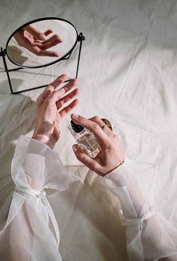 Hands in elegant sheer fabric holding perfume bottle near mirror, creating a graceful reflection. HD phone wallpaper