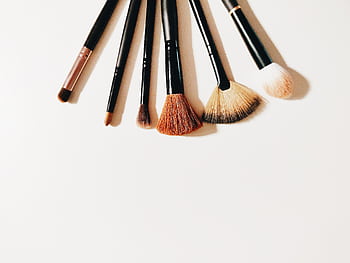 A set of makeup brushes arranged on a white surface, perfect for beauty and cosmetic themes. HD wallpaper