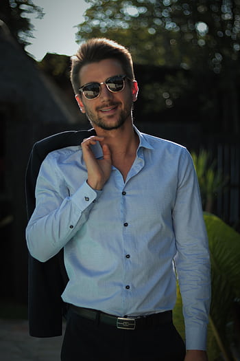 Confident young man in sunglasses poses outdoors in casual attire, exuding style and charisma. HD phone wallpaper