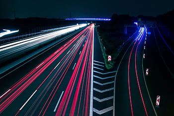 Long exposure of highway light trails creating dynamic motion at night. HD wallpaper