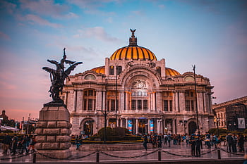 Vibrant sunset at the historic Palacio de Bellas Artes in Mexico City, bustling with tourists. HD wallpaper