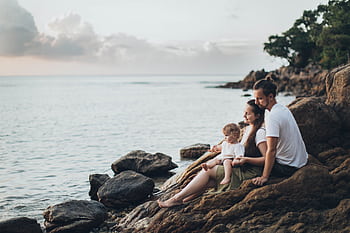 A serene family moment by the seaside, capturing love and relaxation at sunset. HD wallpaper