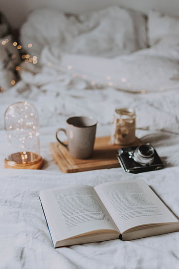 Cozy bedroom with coffee, book, and ambient string lights for relaxation. HD phone wallpaper