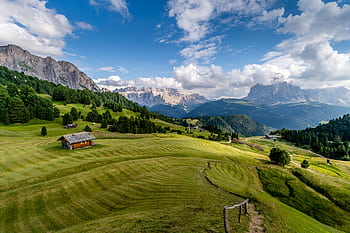 Breathtaking view of rolling hills and mountains in Trentino-South Tyrol, Italy, with clear skies and lush greenery. HD wallpaper