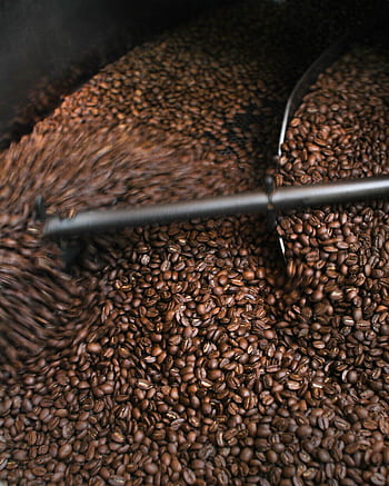 A dynamic close-up of coffee beans being roasted, highlighting the process. HD phone wallpaper