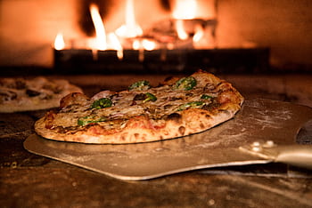 Appetizing gourmet pizza cooked in a wood-fired oven, showcasing artisanal toppings. HD wallpaper