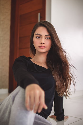 Portrait of a graceful brunette woman with long hair sitting indoors, exuding elegance and style. HD phone wallpaper