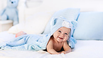 Smiling Cute Toddler Is Lying Down On White Bed Covering With Blue Animal Face Hooded Towel Cute HD wallpaper