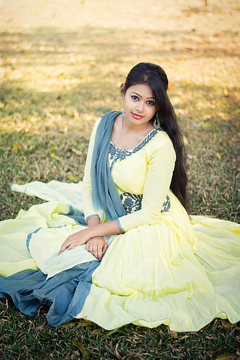 Portrait of a woman in traditional attire, sitting gracefully in a sunny park setting. HD phone wallpaper