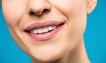 A close-up of a woman's smile with pink lipstick and white teeth against a blue background. HD wallpaper