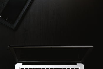 A sleek and minimalist workspace featuring a laptop and smart on a dark surface. HD wallpaper