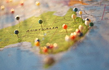 Close-up of a map of Australia with colorful pins marking various cities and destinations. HD wallpaper