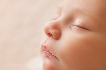 Gentle close-up of a newborn baby sleeping peacefully with soft lighting. HD wallpaper