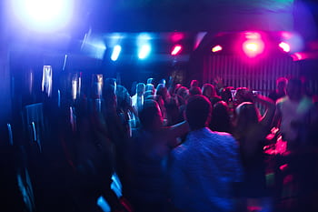 Vibrant nightclub scene with blurred dancing crowd and colorful lights. HD wallpaper