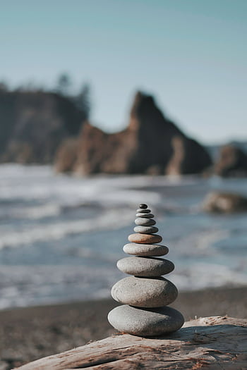 Serene beach scene with stacked stones symbolizing harmony and stability against ocean backdrop. HD phone wallpaper