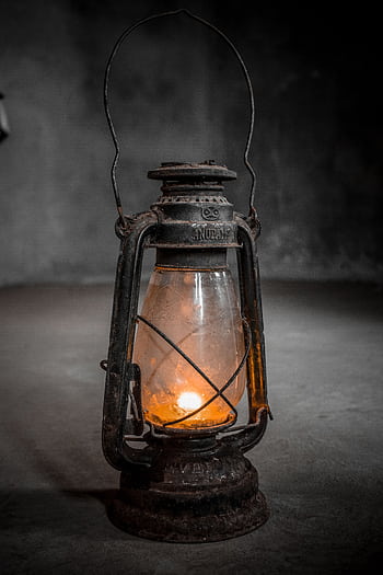An antique lantern illuminated by a candle in a dim room, showcasing vintage charm. HD phone wallpaper