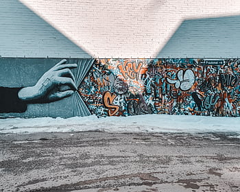 Colorful mural featuring a hand unveiling vibrant graffiti on a street wall. HD wallpaper