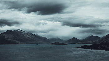 Mystical landscape with cloudy mountains over a serene lake, evoking a sense of calm and mystery. HD wallpaper