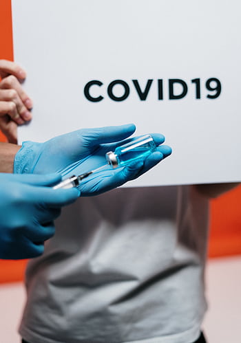 Healthcare worker with syringe and vaccine highlighted by COVID-19 sign. HD phone wallpaper