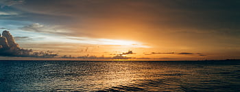 A stunning seascape at sunset with vibrant colors and dramatic clouds over the ocean. HD wallpaper