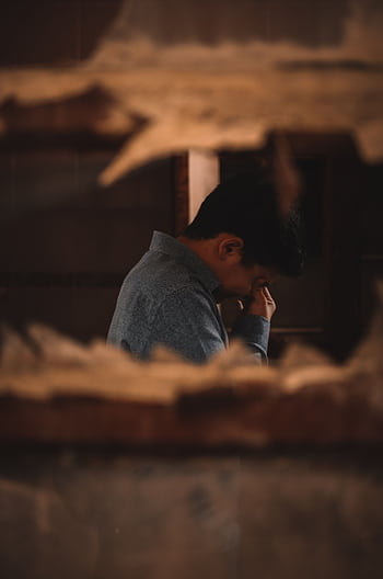A man in deep thought captured indoors through a broken wall. HD phone wallpaper
