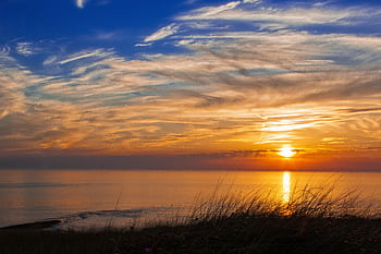 A captivating sunset over the coastal horizon with colorful clouds and calm sea. HD wallpaper