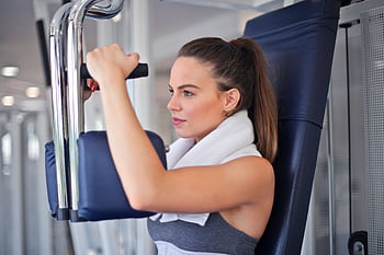 Young woman working out on a chest press machine in the gym, showing strength and determination. HD wallpaper