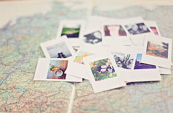 A collection of Polaroid memories spread across a map, symbolizing travel adventures. HD wallpaper