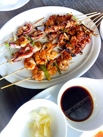 Delicious grilled skewers including shrimp and squid served with sauce on a white plate. HD phone wallpaper