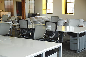 Spacious open office workspace with desks, chairs, and natural lighting. HD wallpaper